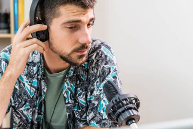 Radyoda radyo sunucusu olarak çalışan adam mikrofonun önünde oturuyor. Genç radyo sunucusu yüz maskeli bir radyo için canlı yayın yapıyor. Evde çalışıyorum. Coronavirüs.