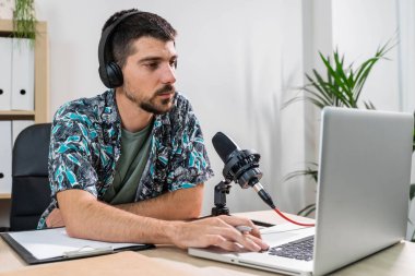 Radyoda radyo sunucusu olarak çalışan adam mikrofonun önünde oturuyor. Genç radyo sunucusu yüz maskeli bir radyo için canlı yayın yapıyor. Evde çalışıyorum. Coronavirüs.