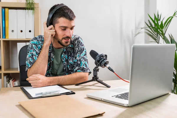 Radyoda radyo sunucusu olarak çalışan adam mikrofonun önünde oturuyor. Genç radyo sunucusu yüz maskeli bir radyo için canlı yayın yapıyor. Evde çalışıyorum. Coronavirüs.