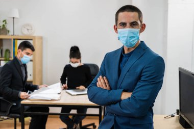 İş adamı portresi. Kilit altında tutulduktan sonra maske takan bir iş adamı işe geri döndü. Güvenli işyeri. Ofis geçmişi. Başarı konsepti. Yeni normallik. Çalışan ev. 