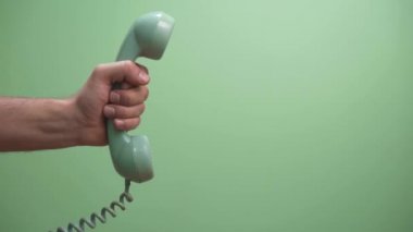 Yeşil arkaplanlı ve fotokopi alanı olan retro yeşil telefon tüpünü tut. Tele market araması bekleniyor..