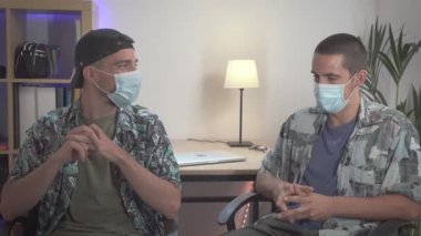 Sosyal medya kanalı internet izleyicileri için kamera önünde 2 genç adam vlogger video röportaj kaydı. Sahne arkasında, sosyal medyada yeni medya yıldızı yaratıcısı var. Coronavirus maskesi.