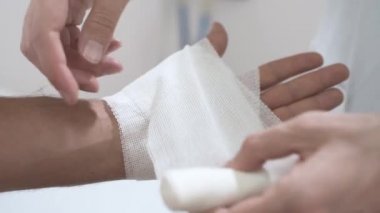 Genç yaralı bir adam erkek travmatoloğu ziyaret ediyor. Doktor hastanın eline elastik bandaj uyguluyor. Dirsek ağrısı. Ortopedi cerrahı. Orta yaşlı adamı muayene ediyor. Omzu, kolu, bileği ağrıyor..