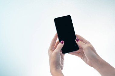 Beyaz arkaplanı olan siyah ekranlı cep telefonu modeli. Masada cep telefonuyla mesajlaşan kadın elleri. Reklam metni için arkaplan boşluğu. İnsanlar pazarlama sektörü ve teknolojiyle iletişime geçiyor.