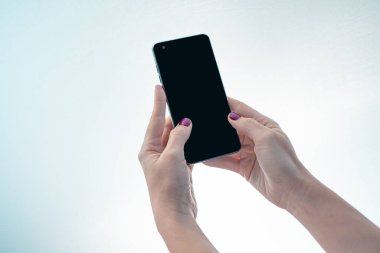 Beyaz arkaplanı olan siyah ekranlı cep telefonu modeli. Masada cep telefonuyla mesajlaşan kadın elleri. Reklam metni için arkaplan boşluğu. İnsanlar pazarlama sektörü ve teknolojiyle iletişime geçiyor.