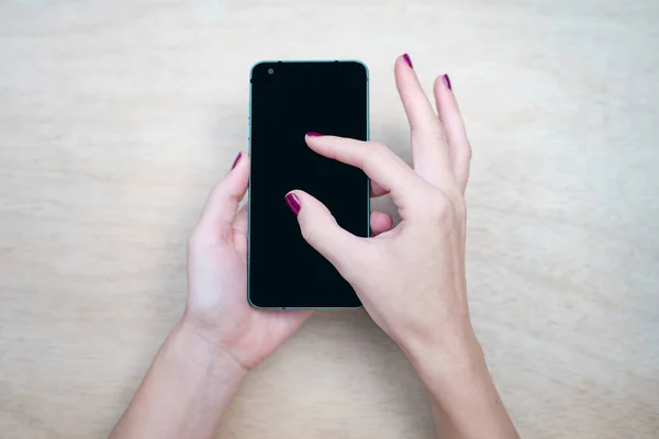 Cell phone mockup image black screen with wood background. Woman hands holding texting using mobile on desk. background empty space for advertise text. People contact marketing business, technology.