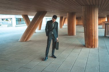 Kendinden emin ve başarılı bir model portresi. Arka planda ofis binası olan yakışıklı bir iş adamı. Metin için alanı kopyala.