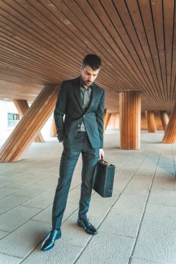 Kendinden emin ve başarılı bir model portresi. Arka planda ofis binası olan yakışıklı bir iş adamı. Metin için alanı kopyala.