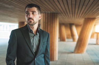 Kendinden emin ve başarılı bir model portresi. Arka planda ofis binası olan yakışıklı bir iş adamı. Metin için alanı kopyala.