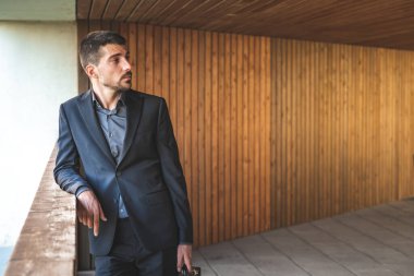 Kendinden emin ve başarılı bir model portresi. Arka planda ofis binası olan yakışıklı bir iş adamı. Metin için alanı kopyala.