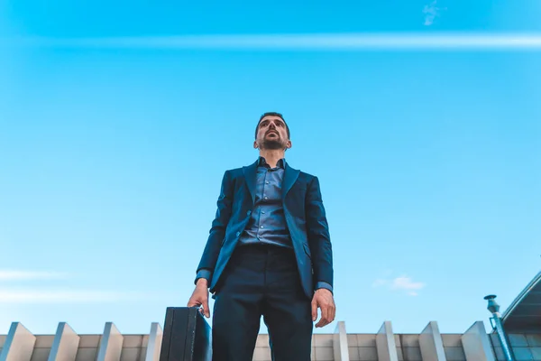 Confident and successful. Handsome young businessman looking away standing outdoors with blue sky in the background.