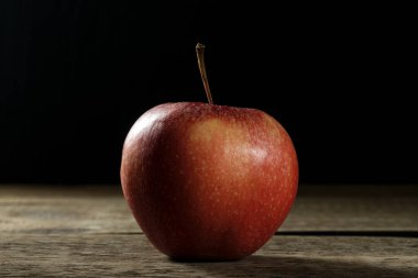 Tahta bir masada taze, biyolojik kırmızı bir elma..