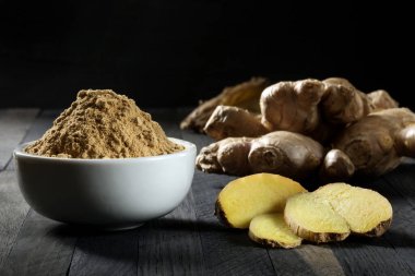 Ground ginger root in a bowl on a wooden table. clipart