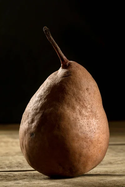 A brown biologic pear on a wooden table.