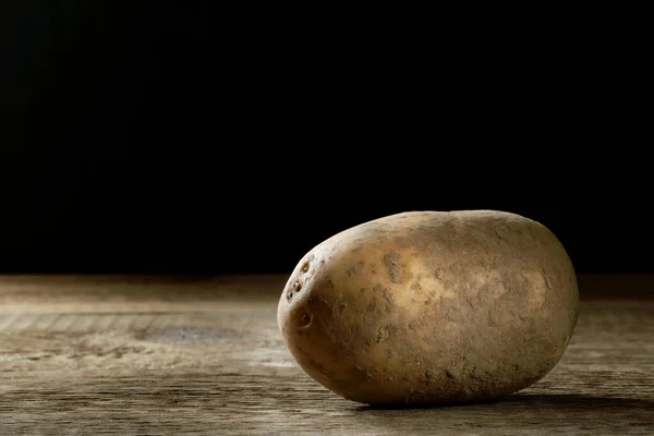 A fresh biologic yellow potato on a wooden table.