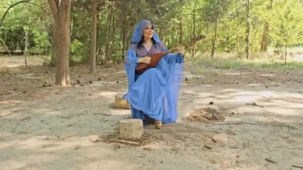 Hermoso estilo árabe en ropa azul étnica, toca el instrumento musical etno — Vídeos de Stock