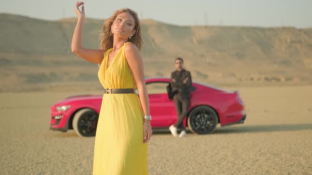 Fashion blonde model in yellow clothes posing in the desert,dried wood,sunny day,a guy and a girl in yellow clothes in the desert — Stock Video