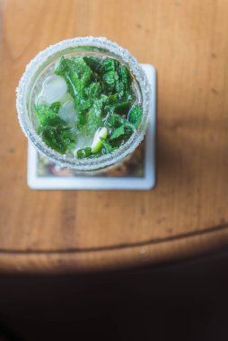 Tahta bir masanın üzerinde bir bardak mojito.