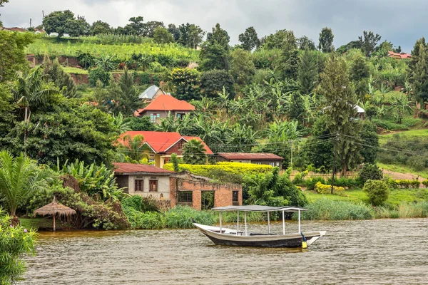 Barco de techo anclado en la costa con pueblo de Ruanda en la parte posterior —  Fotos de Stock