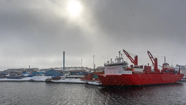 Grand cargo rouge sous le soleil arctique terne et de fortes chutes de neige — Photo