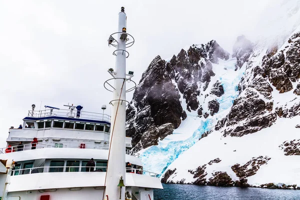 Antarctisch cruiseschip vooraanzicht met mast en enorme steile steen — Stockfoto