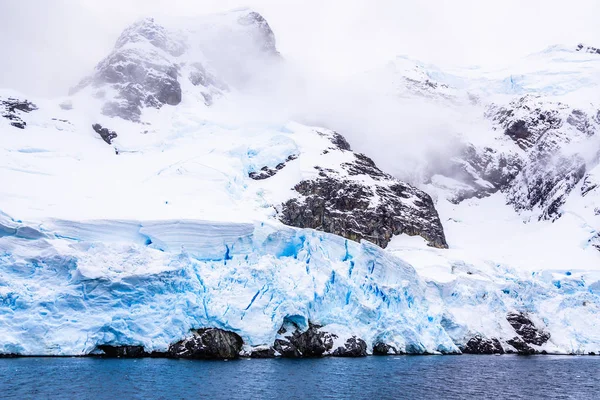 Obrovská strmá skála pokrytá modrým ledovcem a mrakem s w — Stock fotografie