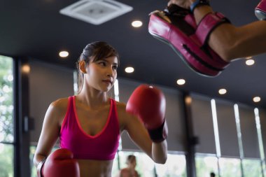 Genç sağlıklı Asyalı kadın spor, spor ve eğlence aktivitesi konseptinde antrenörle boks yapıyor..