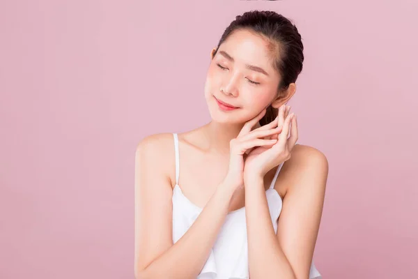 Young happy healthy attractive Asian woman acting like sleeping gesture with smiley face isolated on pink background.