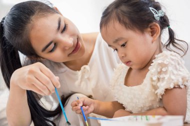 Genç Asyalı güzel anne ve kızı evde oynuyorlar.