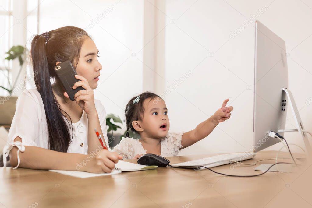 Young Asian beautiful mom with her daughter kid working at home.
