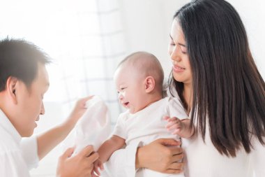 Genç mutlu Asyalı anne baba ve yeni doğmuş bebek tatlı evde oynuyorlar..