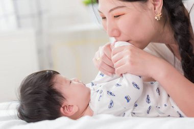 Genç mutlu Asyalı anne, sevgili bebeğiyle evde oynuyor.. 