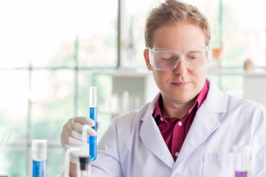 Bilim laboratuarında araştırma yaparken deney tüpüyle test yapan genç beyaz bilim adamları. 