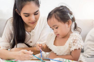 Genç Asyalı güzel anne ve kızı evde oynuyorlar..