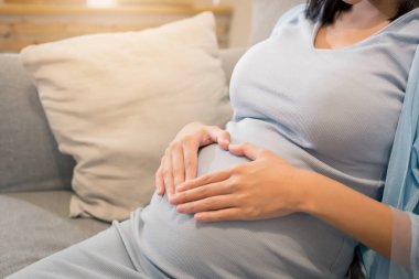 Güzelliğe yakın mutlu Asyalı hamile kadın pencere kenarında büyük bir göbek - hamilelik, annelik, insanlar ve beklenti konsepti.
