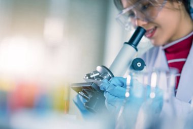 Genç Asyalı tıp teknisyeni kadın deney tüpüyle test yaparken bilim laboratuarında araştırma yapıyor.