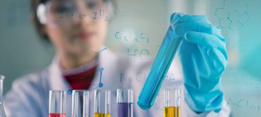 Genç Asyalı tıp teknisyeni kadın deney tüpüyle test yaparken bilim laboratuarında araştırma yapıyor.