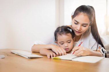 Genç Asyalı güzel anne ve Dougther çocuğu evde çalışıyor..
