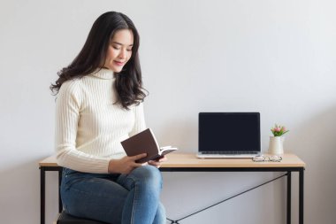 Genç mutlu Asyalı kadınlar kitap okuyor, evde çalışıyor..