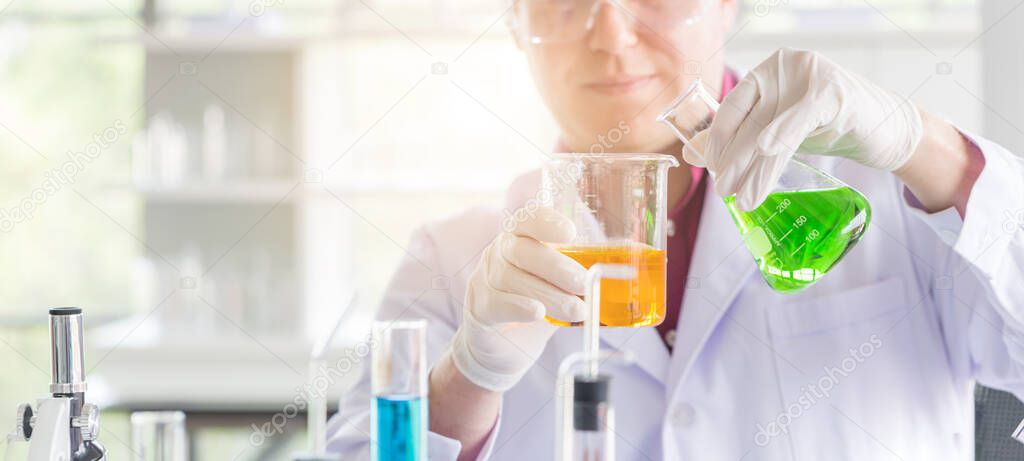 Young Caucasian scientists making testing with test tube while doing research in science laboratory. 