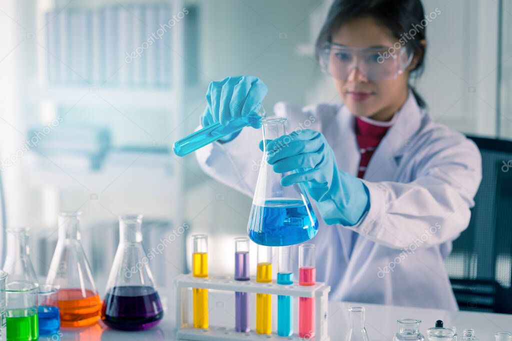 Young Asian medical technologist female making testing with test tube while doing research in science laboratory