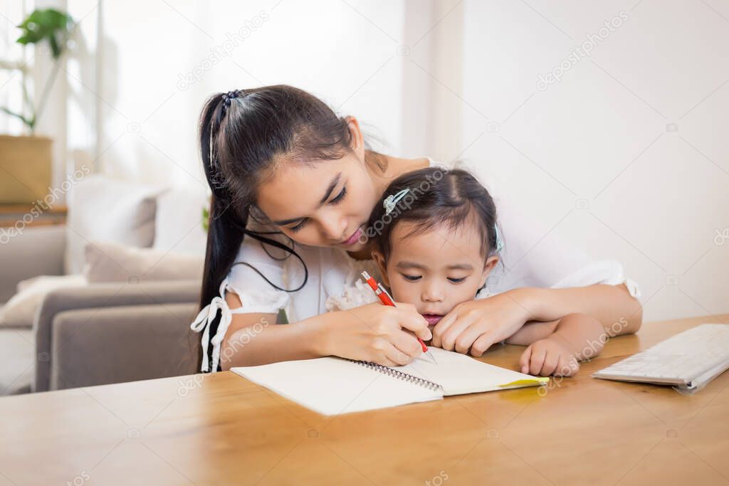 Young Asian beautiful mom with her daughter kid working at home.