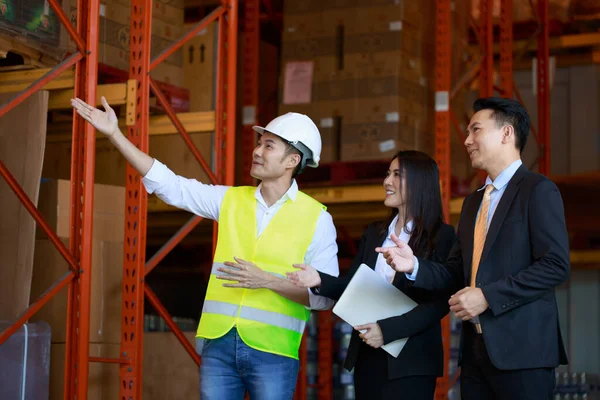 Asian Warehouse manager and male worker as engineer interacting talking checking inventory, manager team working at the storehouse.