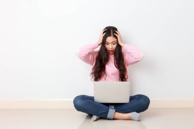 Evde dizüstü bilgisayarla oturan asyalı endişeli, endişeli ve stresli işten korkan genç bir kız öğrenci. İç mekan stüdyo çekimi.