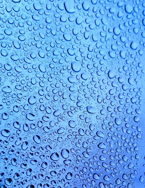 After the rains, raindrops on the glass formed a natural textural pattern. Rainwater gathered in drops on the clear glass of the window.