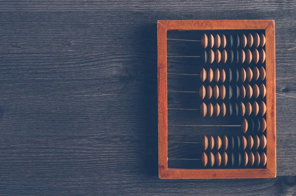 Karanlık arka planda eski ahşap bir abaküs. Muhasebe, iş ya da tasarruf kavramı