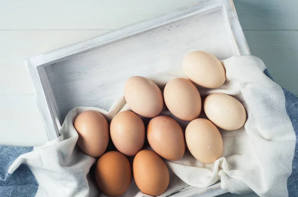 Beyaz arka planda beyaz tahta bir kutuda tavuk yumurtası.