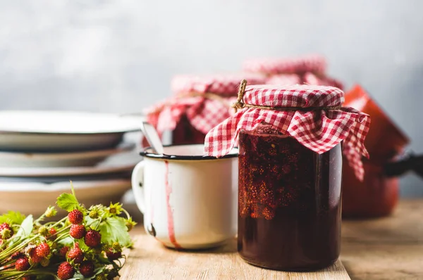 Homemade strawberry jam in jars and inredients on a wooden cutting board