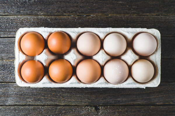 Chicken eggs in a box on a dark wooden background