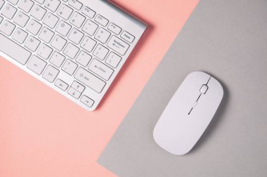 Soluk gri-pembe arkaplanda klavye ve fare